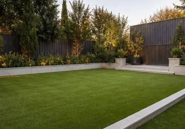 Rectangular lawn framed by a concrete edge and dark fence